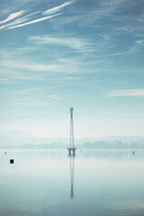 Fototapeta na wymiar Power line tower in the middle of calm Ptuj lake.