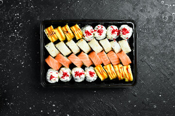 Set of sushi rolls with cheese and fish. Sushi delivery. Disposable tableware. On a wooden board.