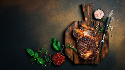 Grilled Black Angus Steak Ribeye and Pepper sauce on meat cutting board on darkbackground. Flat lay