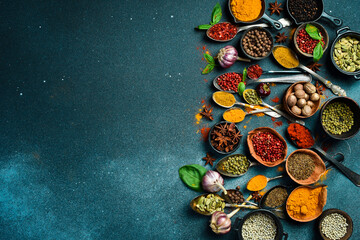 Colored spices in spoons and bowls. Aromatic spices for cooking. On the background of black stone. View from above.