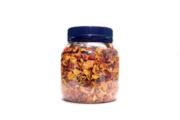 Isolated dried rose petals, leaves, buds in jar, plastic container on pink background on white background. Aromatic herbal beverage, drink made from fragrant buds of desiccated rose flowers.Horizontal