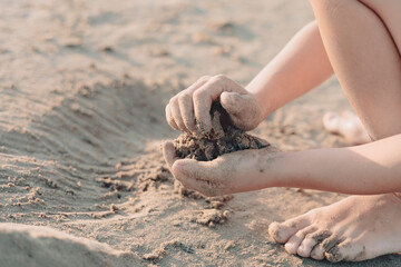 Closeup of childrens hands playing with sand and building castle on summer beach. Vacation concept