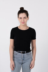 Obraz premium A young brunette girl of European appearance in a black T-shirt and blue jeans on a white background