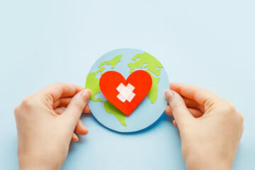 World health day concept. Female hands hold a paper model of the globe with a heart