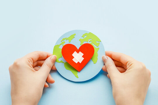 World health day concept. Female hands hold a paper model of the globe with a heart