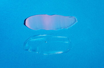Cosmetic samples texture. Smears of transparent liquid cosmetics on a blue background