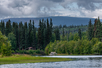 Fairbanks, Alaska, USA - July 27, 2011: Chena River wide landscape with green forest, mountain in...