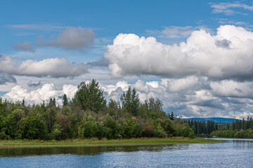 Fairbanks, Alaska, USA - July 27, 2011: Chena River up front under blue cloudscape and green forest belt dividing the image