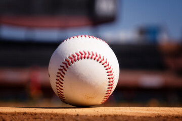 A white leather baseball lying on top of the pitcher's mound