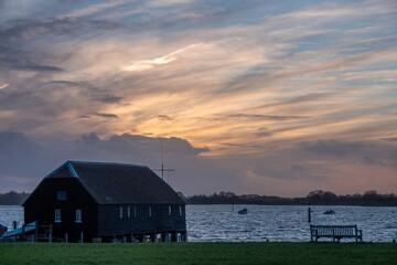Raptackle wooden hut Bosham West Sussex England as the sun sets with a blue and orange cloudy sky in the background