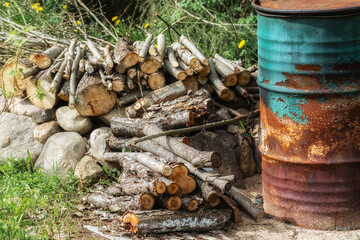 Od rusty iron barrel used for burning garbage in a country garden plot and firewood on stones.