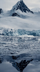 Fototapeta na wymiar Reflecting Snow and Glacier Covered Mountain Peak in Landscape Photo in Antarctica