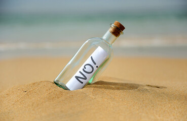 Negative answer, no! Bottle with message on the beach. Bottle with negative answer on the shore