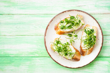 Open sandwich with cream cheese and micro greens at green background. Natural Healthy food, natural vitamins. Top view.