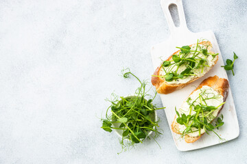 Toast with cream cheese and micro greens. Healthy food, vegetarian dish. Flat lay on white.