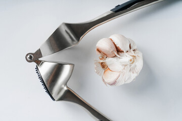 garlic and garlic press on the table on a white background close-up