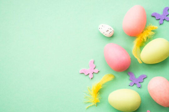 Happy Easter background with colored eggs and butterflies. Flat lay image at green.