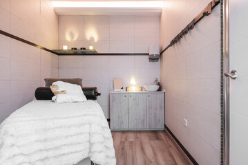 Cabin of a clinic for aesthetic treatments with a massage table, light bulbs similar to candles and...