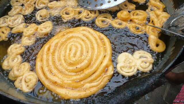 Big Jalebi an indian sweet dish being fried in sugar syrup.Deep oil jilapi frying.