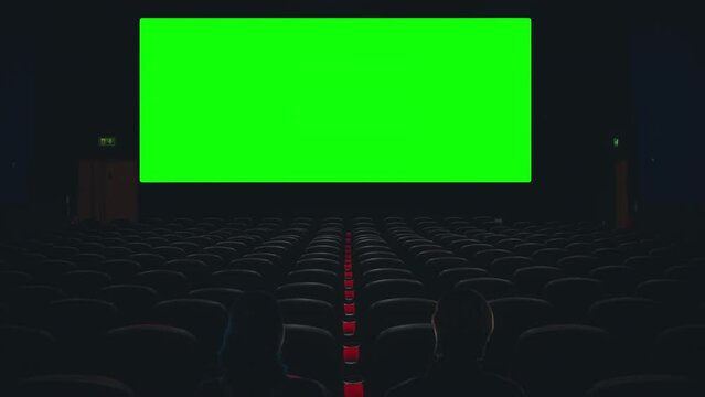 Couple Cinema Theater Green Screen Movie View Zoom In Dark Room. Couple inside a theater watching a green screen projection, zoom in cinema
