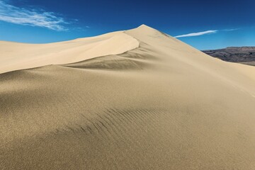 Fototapeta na wymiar Sand dune crest and peak against blue sky