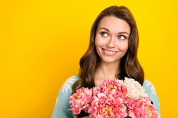 Photo of pretty dreamy lady dressed teal cardigan looking empty space holding flowers isolated yellow color background