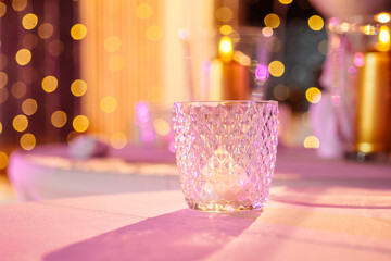 Teelichthalter aus Glas mit angezündetem Teelicht in goldener und Rosa Lichtstimmung am Abend...