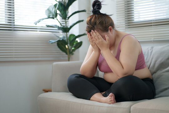 overweight woman sitting on the sofa stress about loss weight.