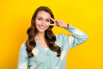 Photo of positive cheerful lady dressed teal cardigan showing v-sign cover eye isolated yellow color background