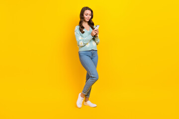 Full body photo of young influencer girlfriend hold smartphone attractive blogger hold smartphone check followers isolated on yellow color background