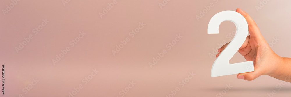Aufkleber Number two in hand. Hand holding white number 2 on red background with copy space. Concept with number two. 2 percent, birthday 2 years old, couple, two, double