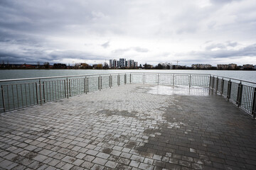 Pier of lake promenade with glass building multistorey residental house on background.
