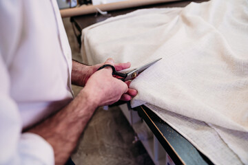 senior man working in atelier cutting curtains. Small business