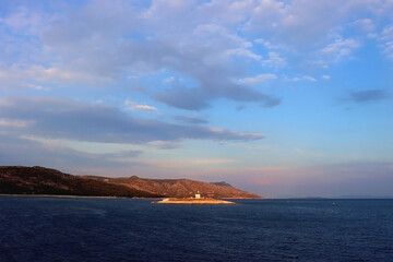 Small lighthouse illuminated by warm sunset light, near island Hvar, Croatia. 