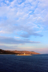 Fototapeta premium Small lighthouse illuminated by warm sunset light, near island Hvar, Croatia. 