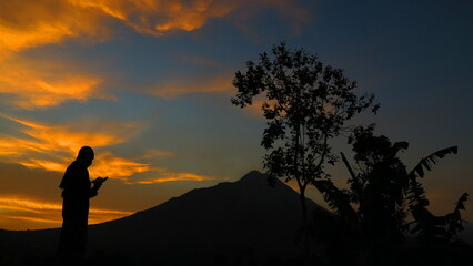 Fototapeta premium Silhouettes of people reading the Qur'an against the background of Mount Merbabu