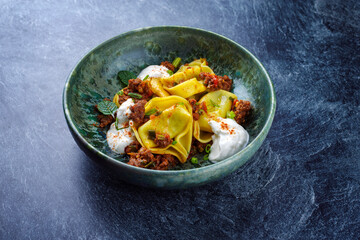 Traditionelle orientalische Manti Teigtaschen mit würzigem Hackfleisch und Joghurt serviert als Nahaufnahme in einer nordischen Design Schale mit Textfreiraum