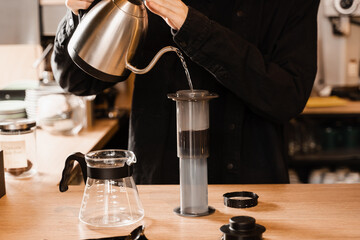 Pouring hot water over roasted and ground coffee beans in aeropress. Process of aeropress...