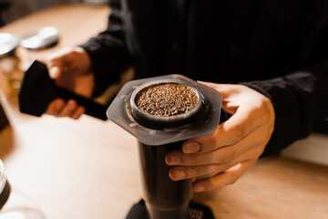 Close-up ground coffee with hot water in aeropress. Process of aeropress alternative method brewing coffee. Pouring hot water over roasted and ground coffee beans in aeropress.