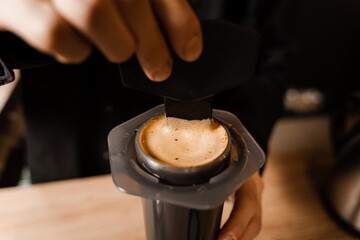 Close-up barista brews Aeropress coffee and stirs it inside. Process of aeropress alternative method brewing coffee.