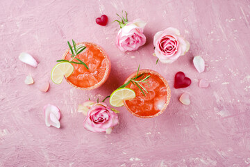 Fototapeta Klassischer Rosa Daiquiri mit Rum, Orangen Likör und Limetten Saft serviert als Valentinstag Geschenk in zwei Gläsern und dekoriert mit Rosen und Herzen obraz