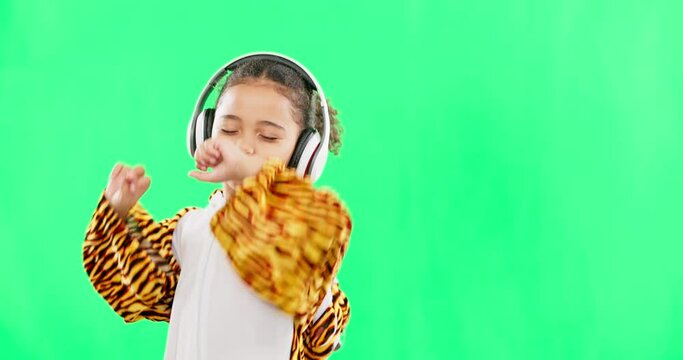 Children, music and a girl dancing on a green screen background in studio streaming audio while having fun. Kids, energy and freedom with a little female child dancing while listening to the radio