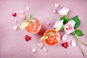 Fototapeta Klassischer Rosa Daiquiri mit Rum, Orangen Likör und Limetten Saft serviert als Valentinstag Geschenk in zwei Gläsern und dekoriert mit Rosen und Herzen obraz