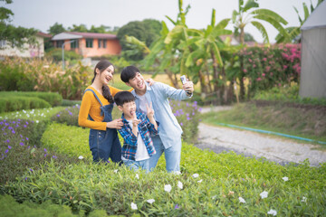 Naklejka na ściany i meble Lovely asian family take selfie in garden, travelling with parent, relationship in family concept, mother, father and son enjoy their lifestyle in nature.