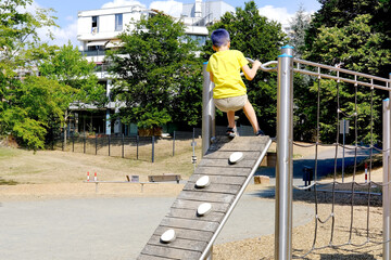 child, boy 7-8 years old in yellow T-shirt, shorts performs barefoot, trains on the sports ground...