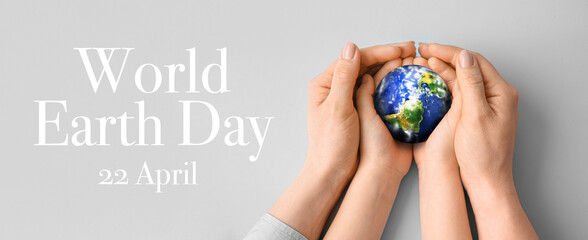 Hands of mother and child holding small planet on grey background. World Earth Day - Powered by Adobe