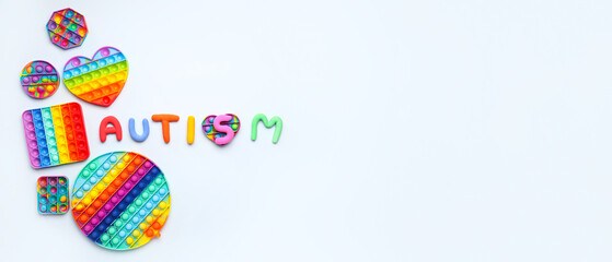 Word AUTISM and pop it fidget toys on white background with space for text