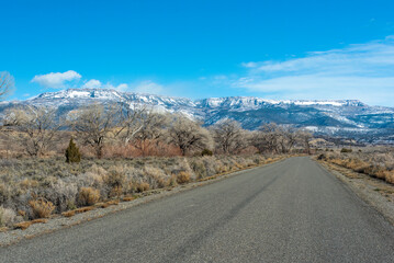 Naklejka premium Road on Reeder Mesa in the Grand Valley, Colorado, heading toward the snowy Grand Mesa in winter 