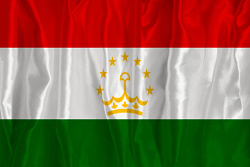 The flag of Tajikistan on a silk background is a great national symbol. Texture of fabrics The...