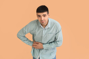 Young man with appendicitis on beige background
